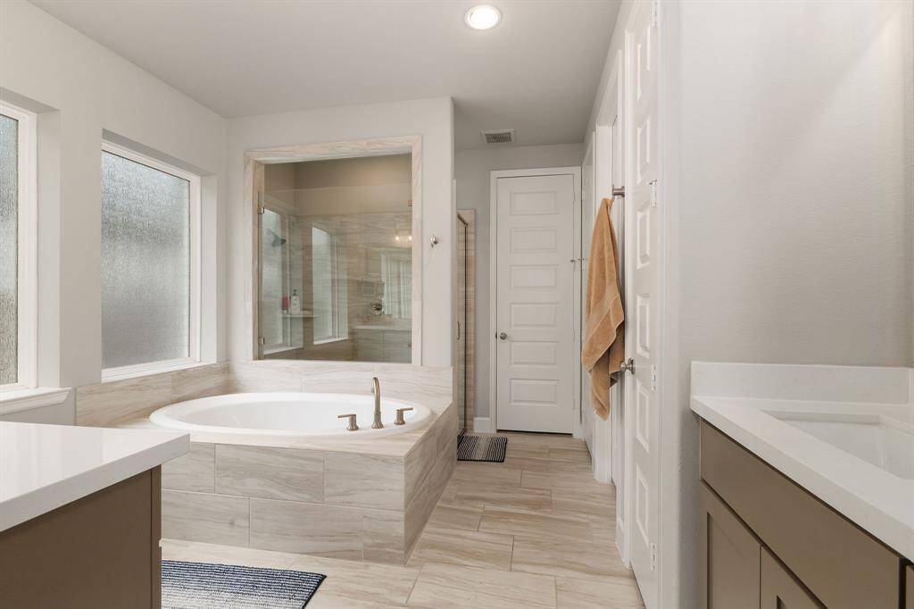 The primary ensuite bathroom is a luxurious retreat designed to offer ultimate comfort and relaxation. It features elegant dual quartz-topped vanities that provide ample space for two, complemented by sleek fixtures and plenty of storage.