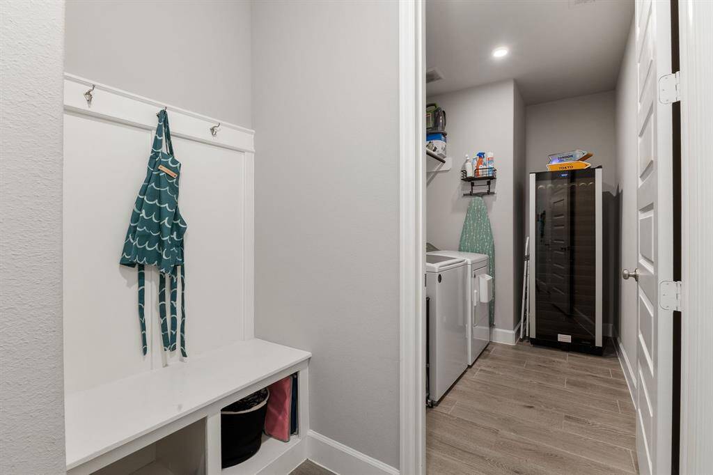 The mud area offers a dedicated spot to drop shoes and hang coats with a bench, cubbies, and overhead hooks. It leads to a large laundry room with space for full-size appliances plus a deep freezer or extra fridge.