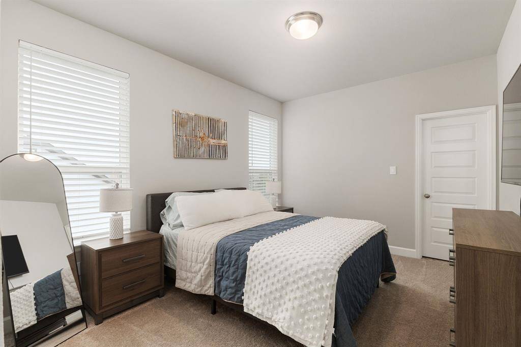 The first secondary bedroom offers a bright and welcoming retreat, featuring plush carpeting for added comfort, a high ceiling that enhances the sense of space, and large windows that fill the room with natural light.