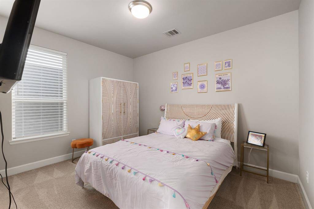 This spacious secondary bedroom is designed with comfort in mind, featuring plush carpeting, a high ceiling that enhances the room’s open feel, and a large window that welcomes abundant natural light.