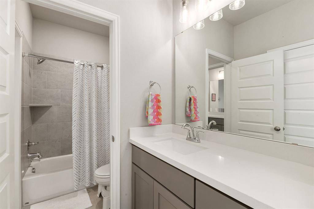 The Jack and Jill bathroom features a quartz-topped vanity with elegant lighting, and a shared area housing the commode alongside a tub and shower combo—combining style and functionality for easy, convenient use.