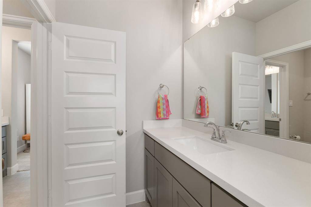 The Jack and Jill bathroom features a quartz-topped vanity with elegant lighting, and a shared area housing the commode alongside a tub and shower combo—combining style and functionality for easy, convenient use.