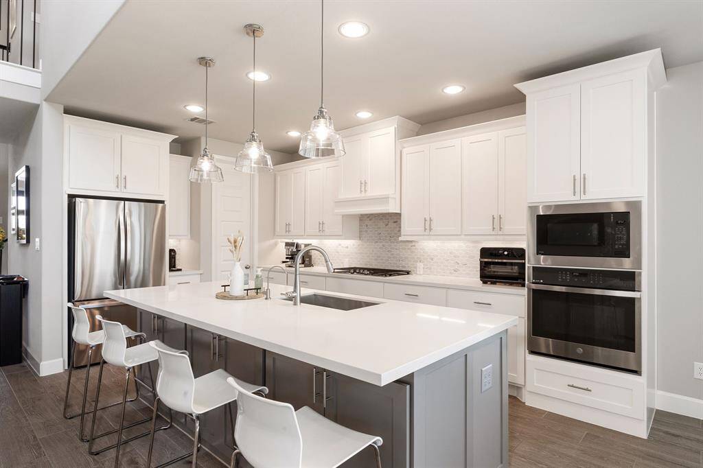 This stunning kitchen features a stylish breakfast bar with elegant pendant lighting and generous storage underneath. A built-in oven and microwave provide convenient, versatile cooking options for any culinary enthusiast.