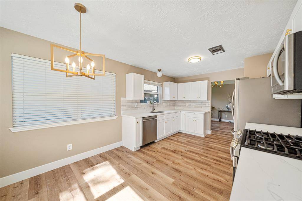 Stylish Modern Kitchen: Featuring Caracara countertops, a farmhouse sink, chic backsplash