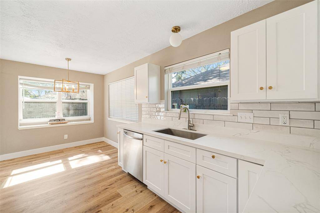 A luminous, modern kitchen with Caracara countertops, a farmhouse sink, and abundant natural light.