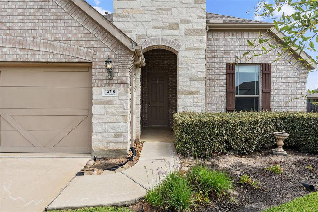 Stone and brick exterior along with coach lamp lighting and rain gutters.