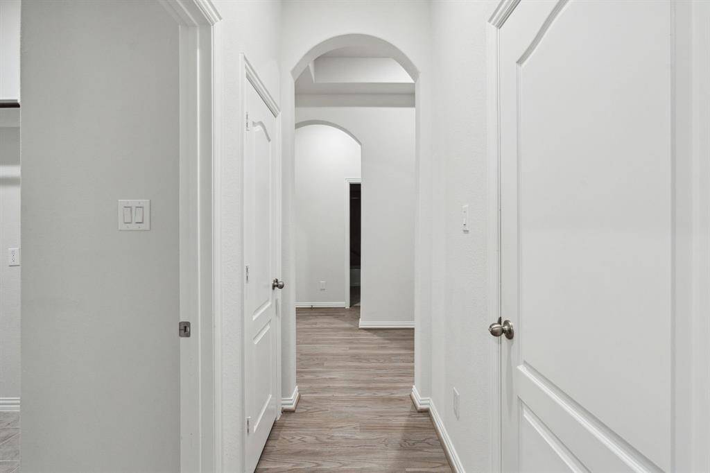 Hallway from flex room towards foyer with laundry on the left and garage on the right