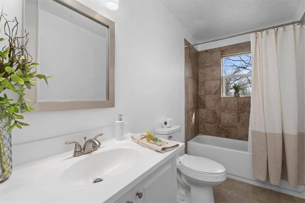 This stunning bathroom showcases a new vanity, faucet, toilet, tub/shower and window!