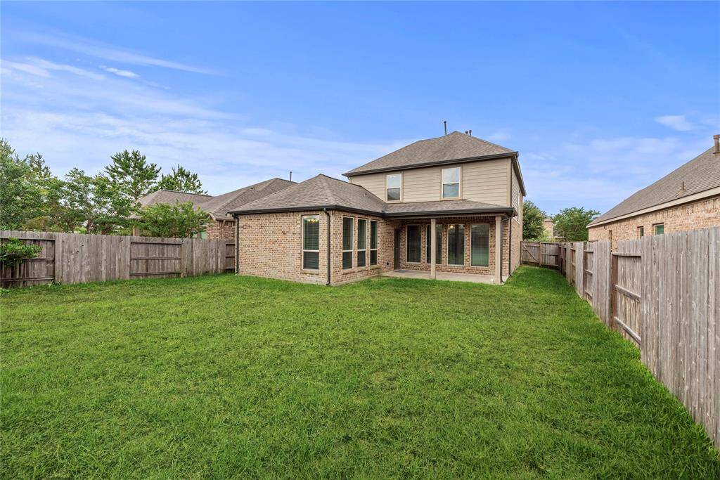 Outside, a covered backyard patio perfect for al fresco dining and relaxation, overlooking the landscaped yard.
