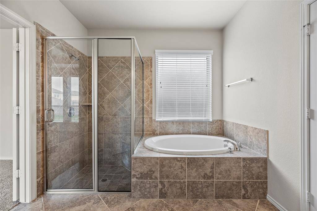 The primary bath is a luxurious escape, featuring a garden tub, separate glass-enclosed shower, dual sinks, and a generously sized walk-in closet, providing both comfort and functionality.