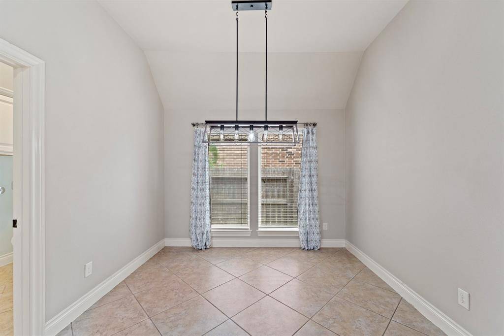 Charming dining nook off the kitchen features a decorative chandelier and oversized baseboards.A cozy space ideal for casual meals with a view of the backyard.