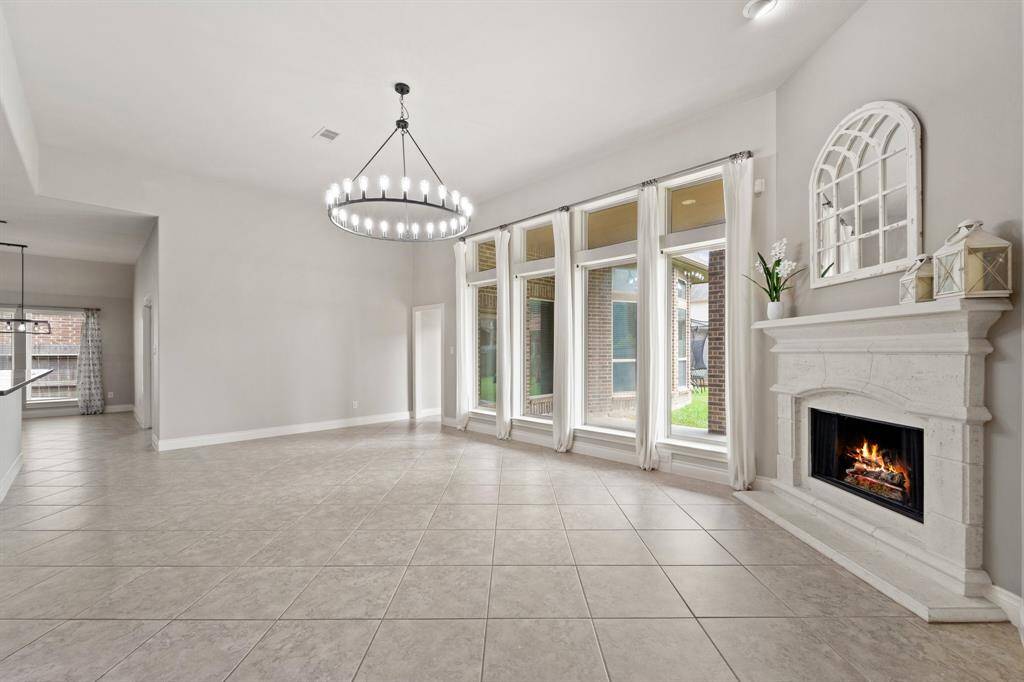 Spacious living room featuring a cozy fireplace, ample room for seating, and an abundance of natural light.Perfect for relaxation or entertaining, with large windows enhancing the airy atmosphere.