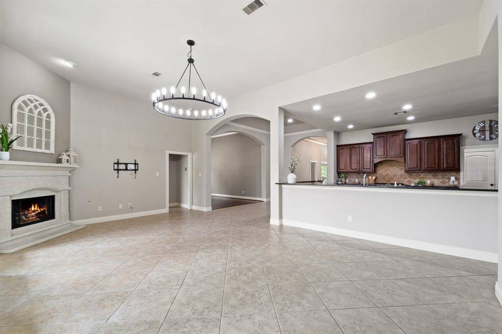 The living room seamlessly connects to the kitchen via a convenient counter, enhancing the open and airy layout.A large chandelier adds elegance, complemented by stylish baseboards throughout. Ideal for easy interaction and entertaining between spaces.