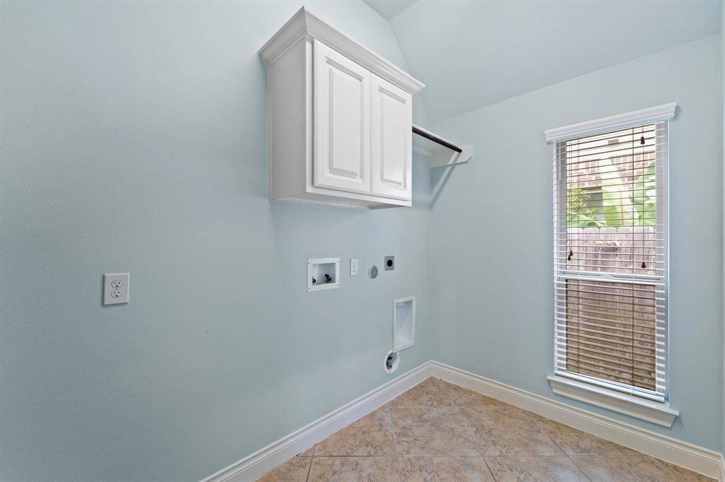 Functional laundry room with built-in cabinetry for storage and a designated rack space for an extra fridge.