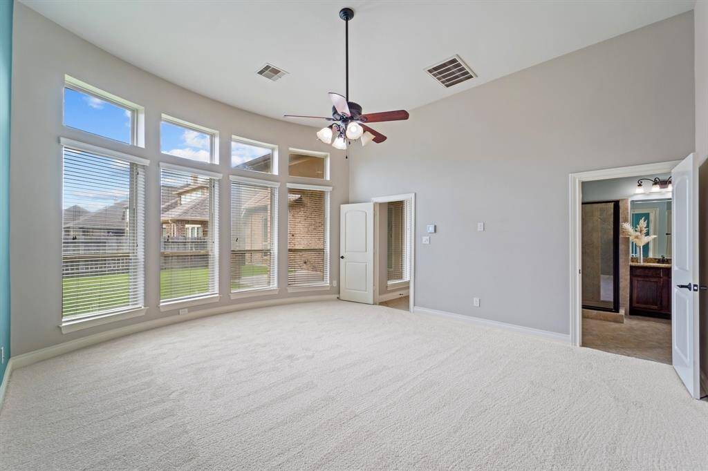 Carpeted primary bedroom featuring large windows with blinds for natural light and privacy.A comfortable and serene retreat designed for restful living.