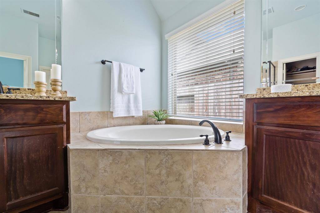 The tiled tub is beautifully positioned next to a window in the corner, allowing natural light to enhance your bathing experience.