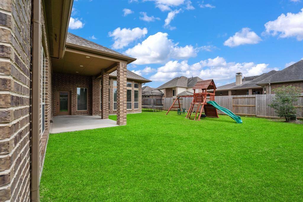 Newly installed back fence encloses a spacious backyard with a covered brick patio, perfect for outdoor gatherings.