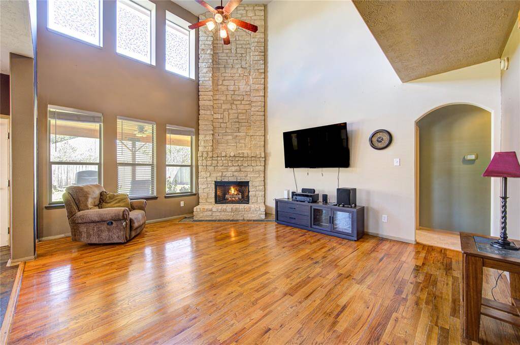 2 story open concept living room with a cozy fireplace with beautiful real wood floors