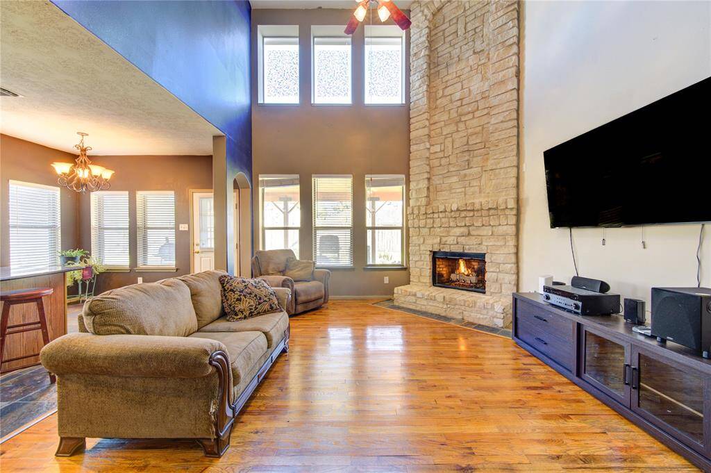 2 story open concept living room with a cozy fireplace with beautiful real wood floors
