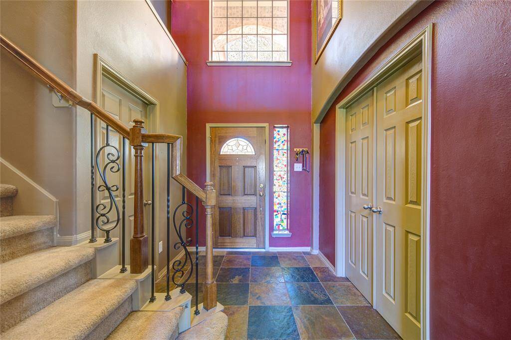 Entrance of home with beautifully crafted wooden handrail and traditional wrought iron balusters with the indoor utility room behind the door to the left and the private office to the right