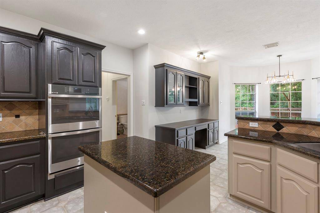Elevate your culinary experience with double ovens, ideal for entertaining. The stylish black cabinetry offers versatile space for a dry bar or workspace.