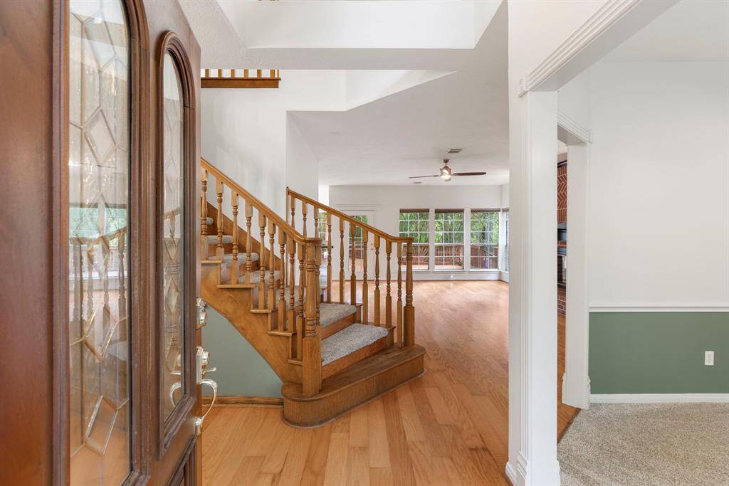 This inviting home features a welcoming entry leading into a spacious living area with hardwood floors and large windows offering plenty of natural light.