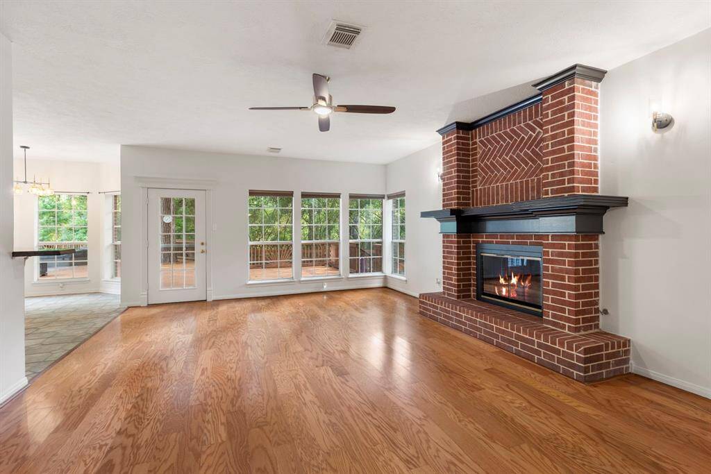 Spacious living room featuring a stunning brick fireplace and abundant natural light through expansive windows. Ideal for cozy gatherings.