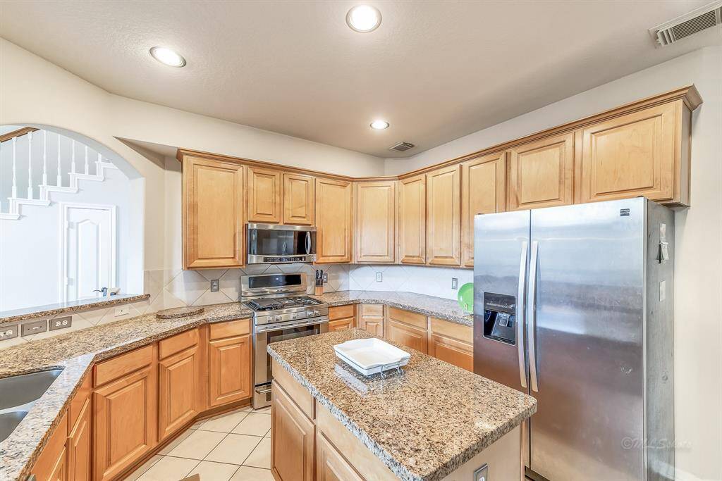 Island kitchen with granite countertops, stainless steel appliances, and plenty of storage for serious chefs. The island has power outlets, making it the perfect prep station. Stainless steel refrigerator included.