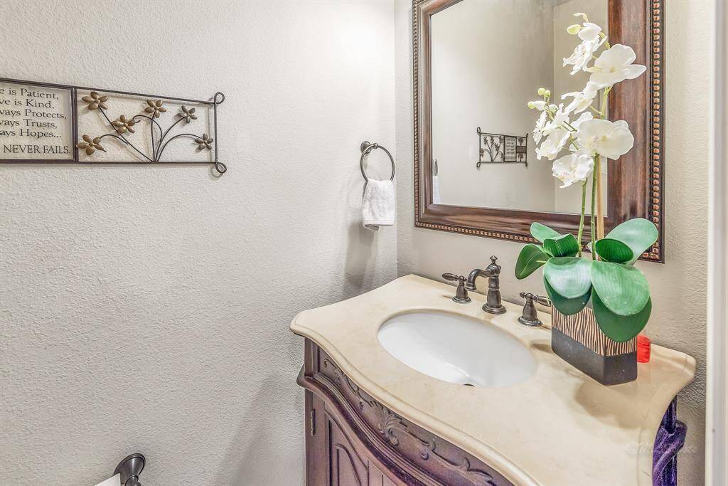 The half-bath is located on the first floor with granite-topped vanity and furniture-style sink stand.