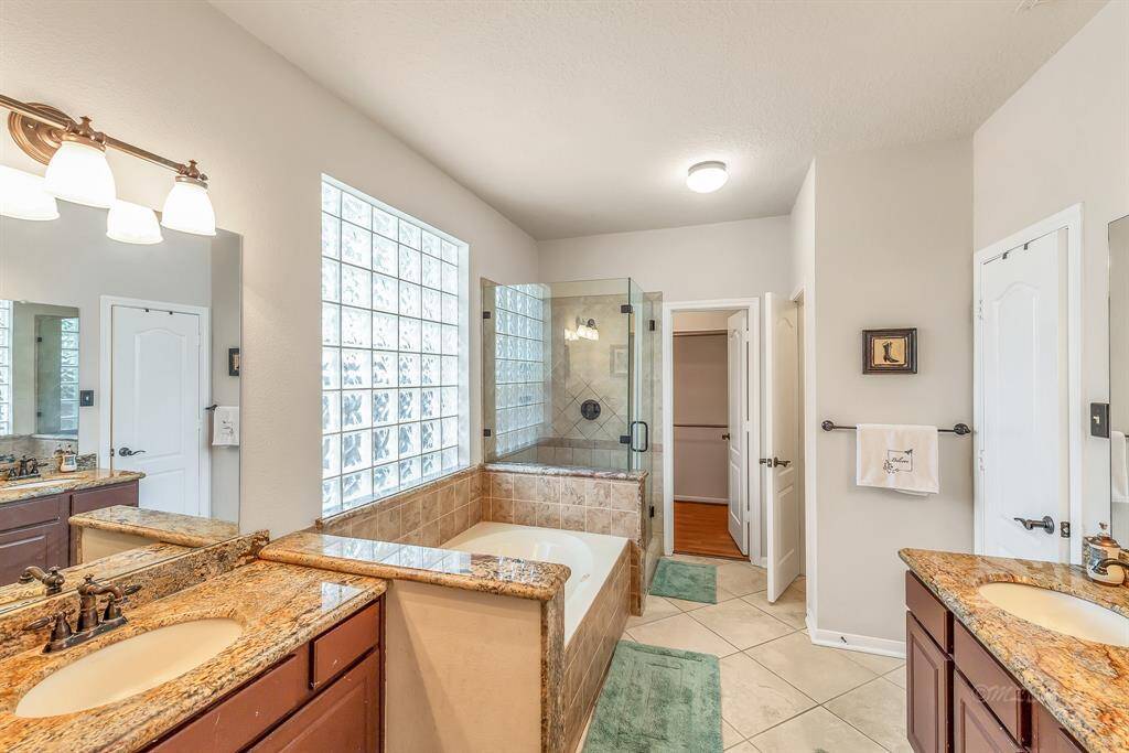 Upon entering the master bath, you can see the separate sink and vanity spaces, updated fixtures, and separate soaking tub and glass-enclosed shower. Glass-block windows provide privacy while allowing this space to be filled with natural light.