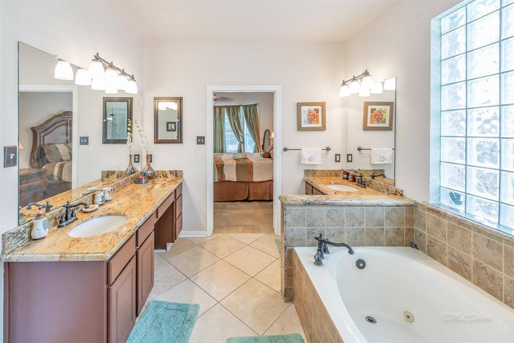 The light-filled master bath features a whirlpool tub, double sinks with granite countertops, and plentiful counter and vanity space.