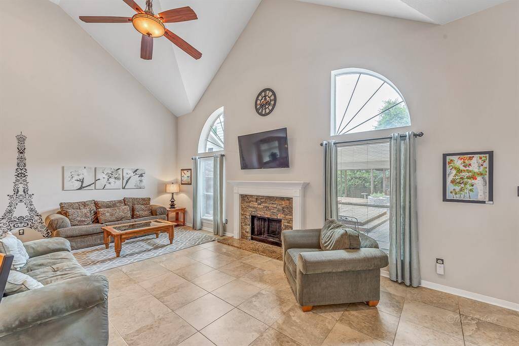 The downstairs living area with gas fireplace and high ceilings is an inviting entertaining area with room for multiple seating arrangements.  The large windows provide a view to the backyard and covered patio. Smart TV allows access to enterainment via wi-fi.