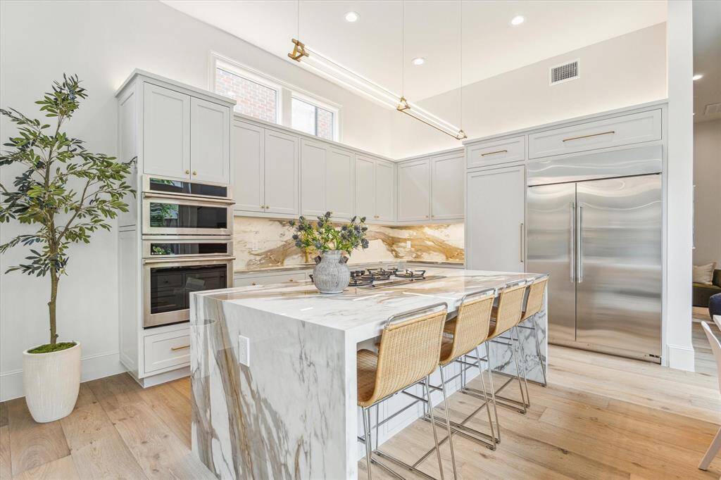 The open-concept gourmet kitchen is a chef’s dream, featuring a modern gas cook-top, double ovens, and stainless steel appliances.