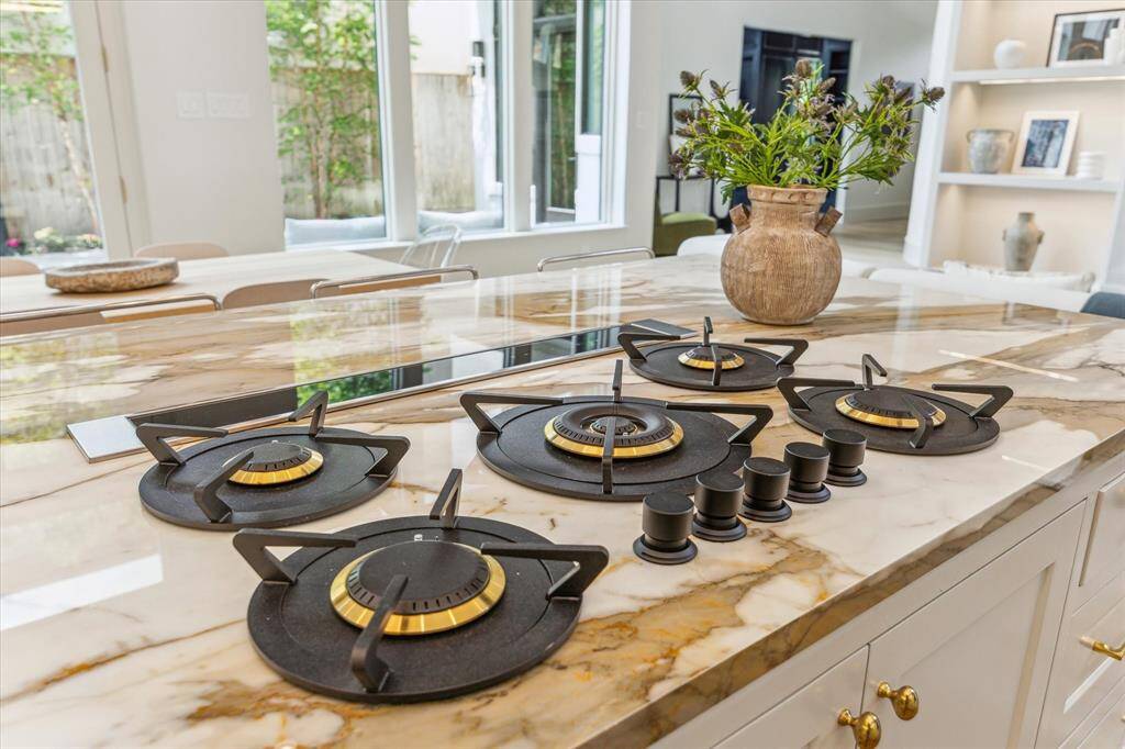 An up-close look at the designer gas cooktop—set into a show-stopping slab of marble—showcases the refined craftsmanship and luxury finishes throughout the kitchen.