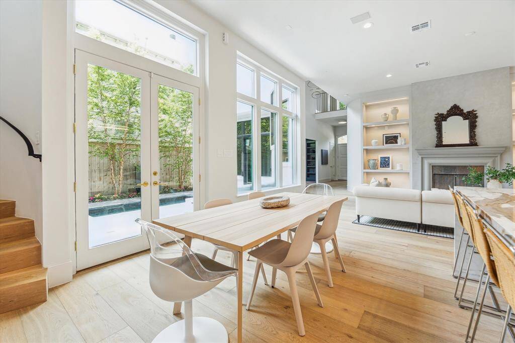 Floor-to-ceiling windows and French doors frame views of the courtyard, bringing in lush green serenity to this open-plan design.