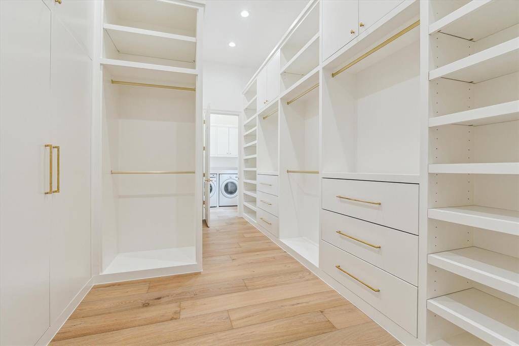 The primary closet is a fashion lover’s dream, with extensive custom cabinetry, brass hardware, and a seamless flow into the laundry room.