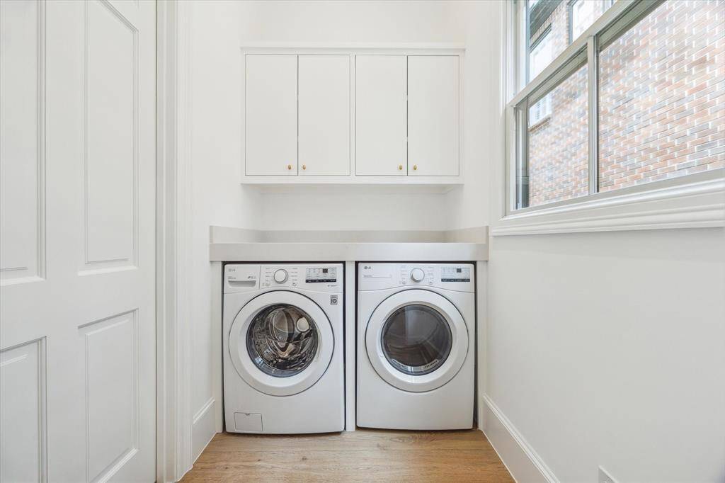 Tucked away just off the primary closet, the laundry room offers functional ease with front-load appliances, overhead cabinetry, and natural light through a picture window.