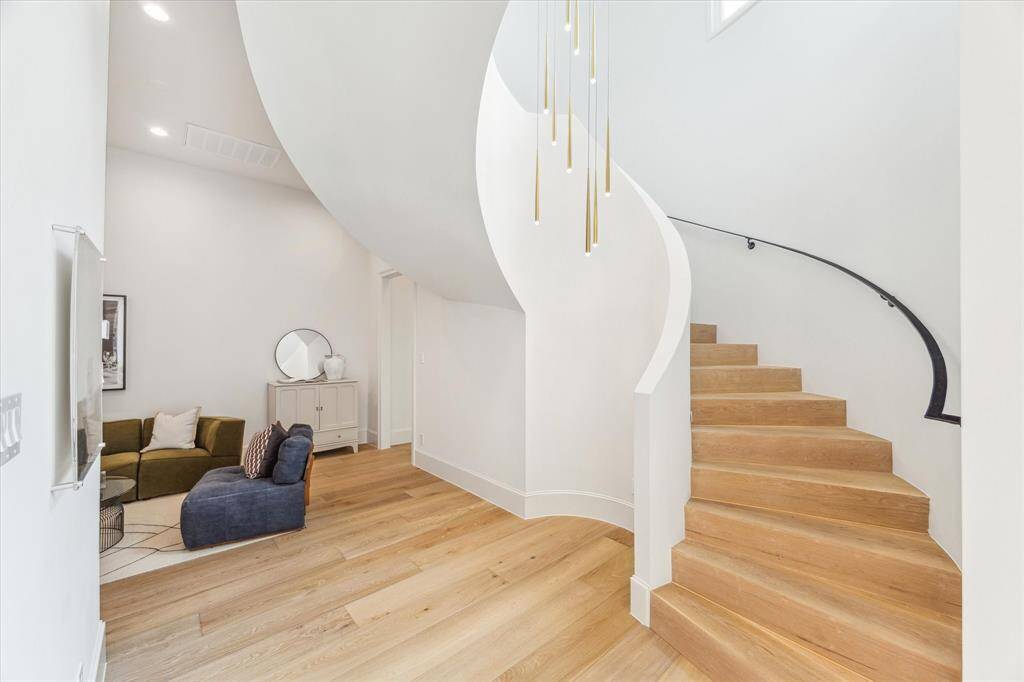 Sweeping spiral stairs and soft natural light add architectural drama to the rear of the home, creating a sense of graceful movement.