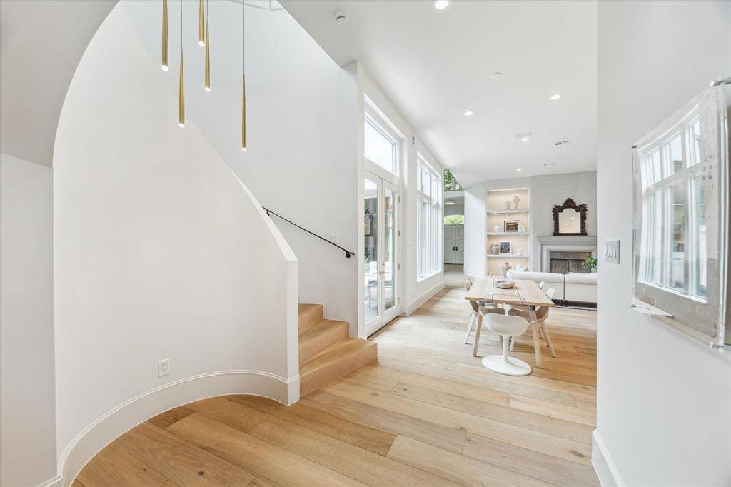 The sculptural staircase curves gracefully upward, accented by sleek brass pendant lighting and warm oak treads—an architectural focal point that’s both elegant and inviting.
