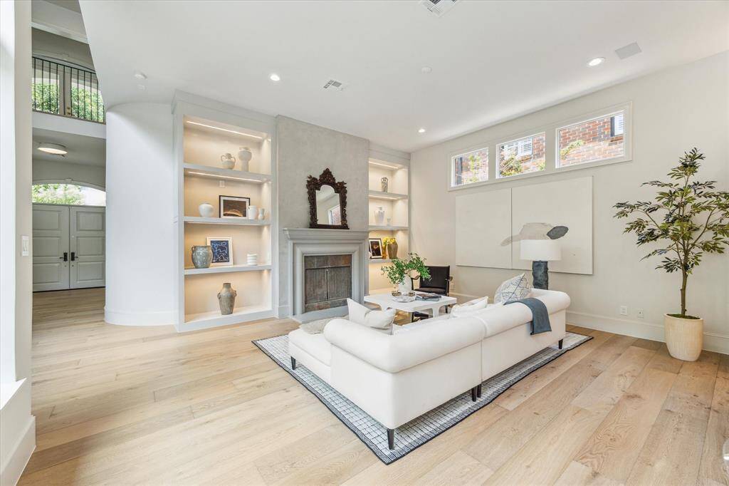 A refined living area anchored by a minimalist fireplace and built-in shelving, offering warmth, light, and modern elegance in perfect harmony.