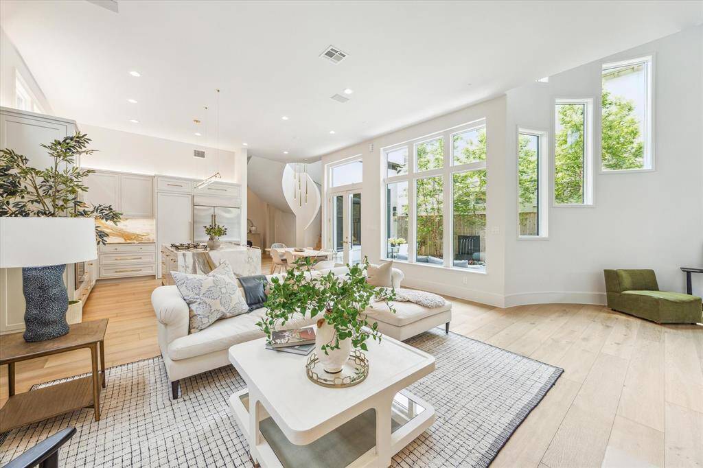 Entertain effortlessly in the spacious living room, where a dramatic wall of glass windows frames the beautifully landscaped courtyard and serene wall fountains, creating a seamless blend of indoor-outdoor living.