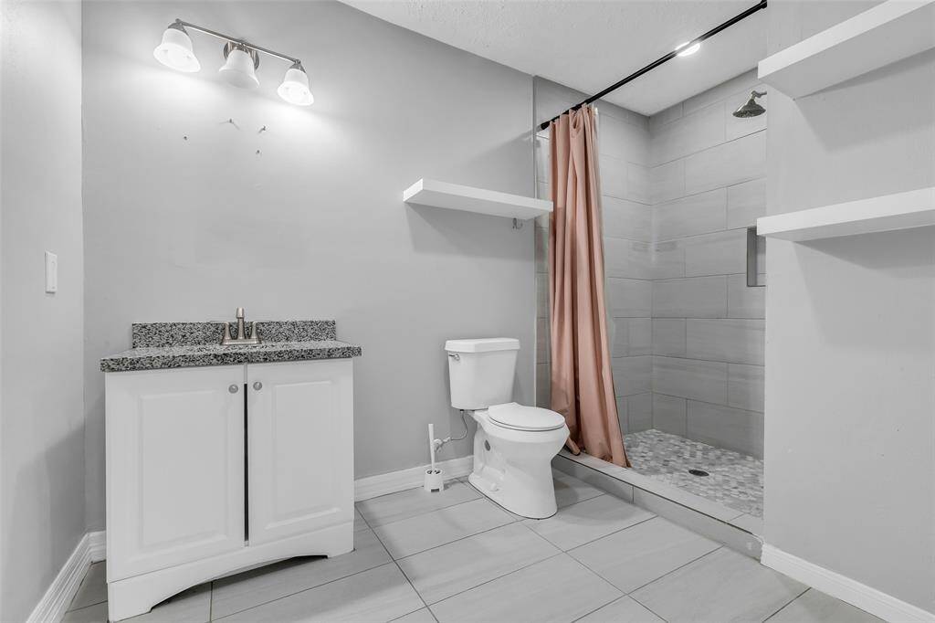 The main bathroom features a shower area, a single sink, and floating shelves for convenient storage of your toiletries.