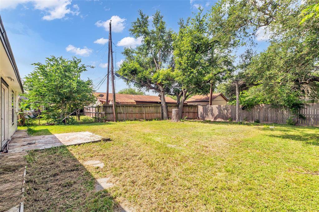 Welcome to the backyard, featuring an open patio and a tall wooden fence that encloses the entire area, providing privacy and a great space for outdoor activities.