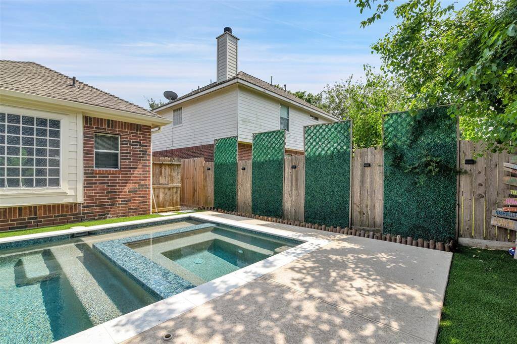 This backyard features a modern pool with a sleek design, surrounded by a privacy fence with greenery accents. Perfect for relaxation and entertaining.