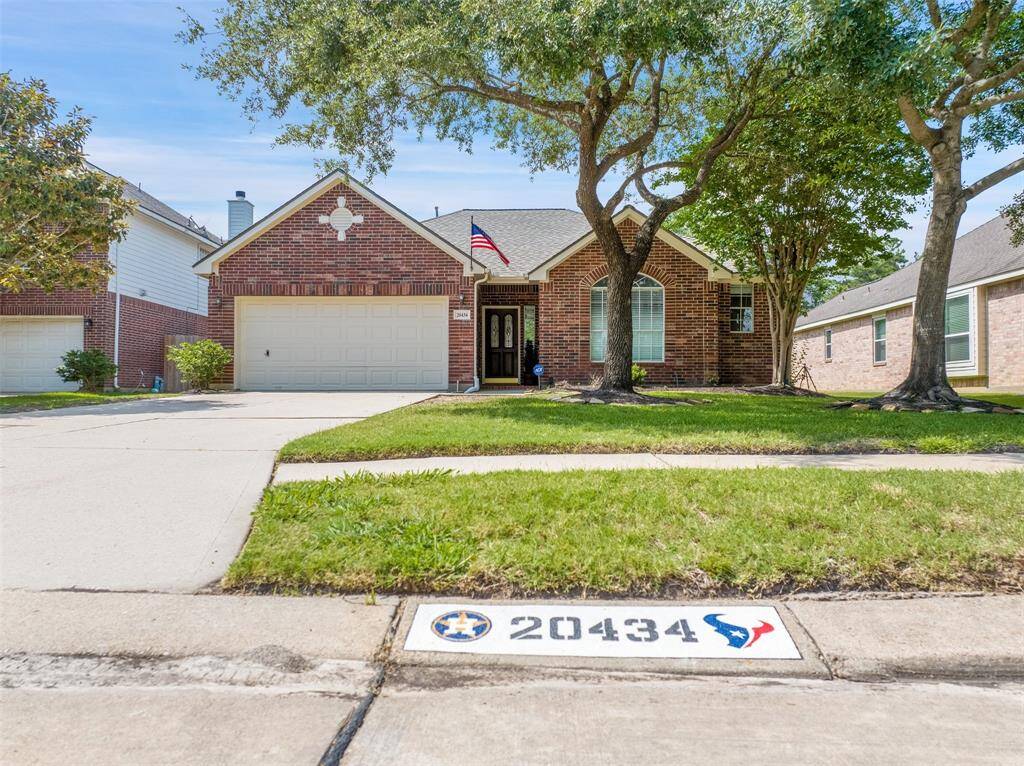 Charming single-story brick home with a well-maintained lawn and mature trees. It features a two-car garage and a welcoming front entrance, set in a quiet neighborhood.