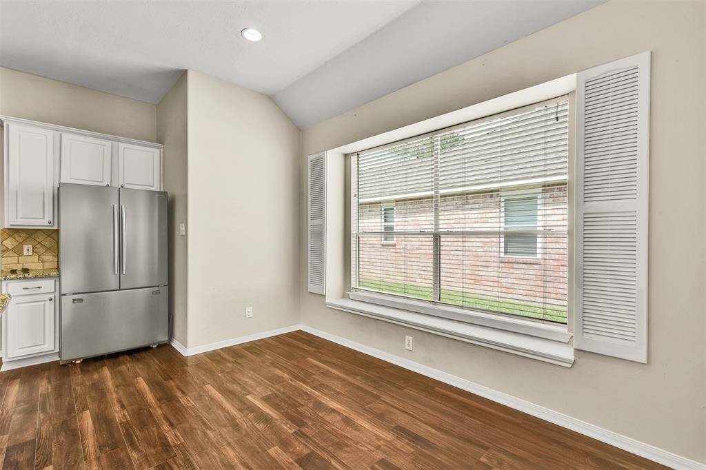 This inviting living room features a cozy fireplace! The open layout connects to a modern kitchen with white cabinetry and granite countertops. The neutral tones and ample lighting create a warm, welcoming atmosphere.