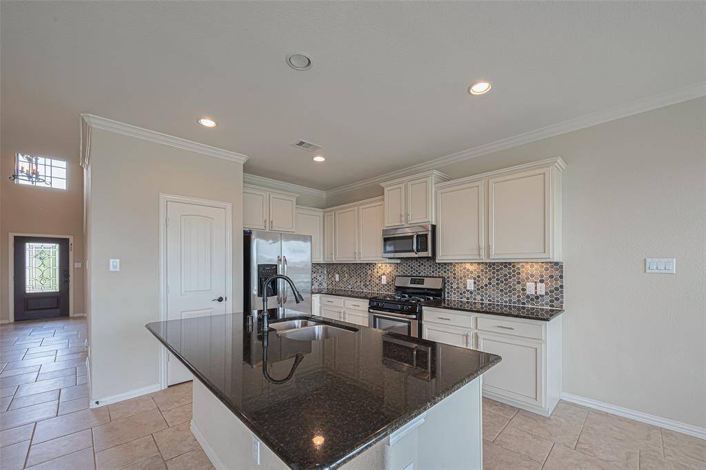 Crisp white cabinetry contrasts beautifully with a rich backsplash, while the black granite countertop on the island adds depth and modern elegance.
