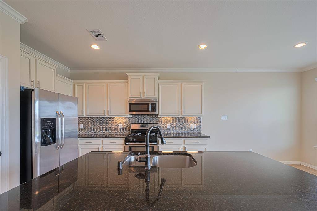 The kitchen island features a sleek undermount sink, its surfaces glowing under the soft halo of recessed lighting overhead.