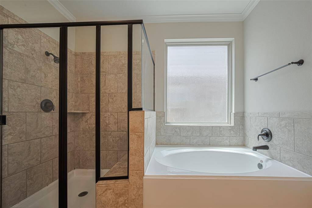 The shower’s black-trimmed glass enclosure and matching fixtures pair beautifully with the soaking tub tucked beneath a frosted window.