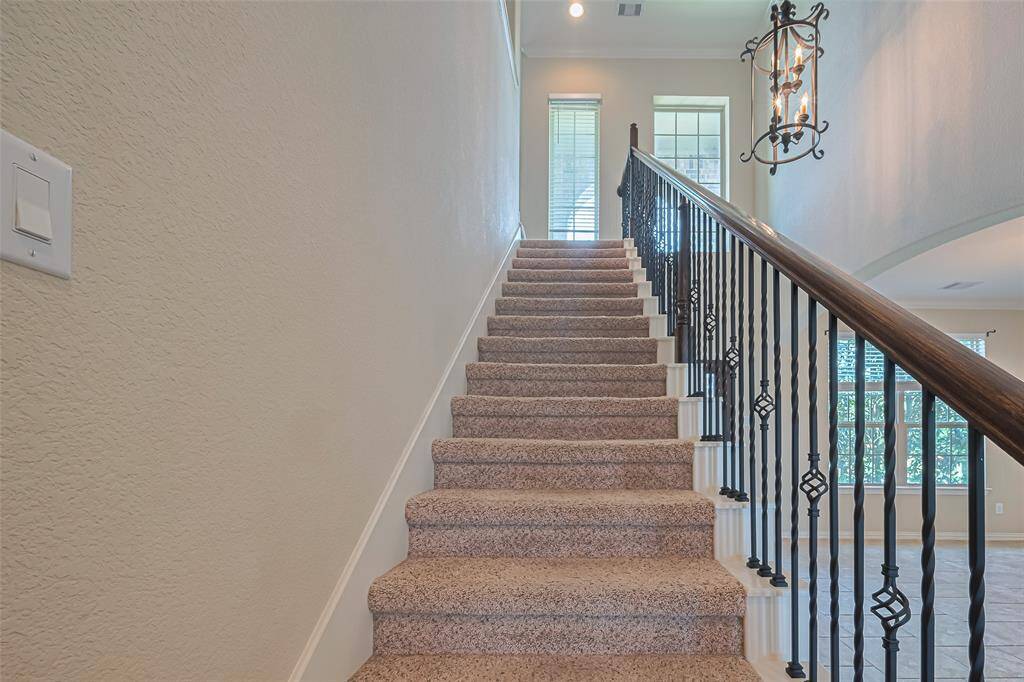 The staircase ascends with grace, accented by classic iron balusters and a pendant light that casts a soft glow on every step.